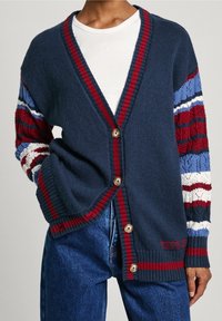 Cardigan navy con maniche a maglia a righe rosse e blu, caratterizzato da un collo a V, cinque bottoni frontali e polsini e orlo a costine.