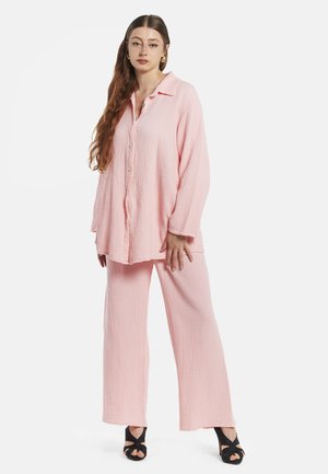 Conjunto de loungewear de gasa rosa claro que incluye una camisa de botones de manga larga con cuello y pantalones de pierna ancha, de tejido texturizado y diseño minimalista.