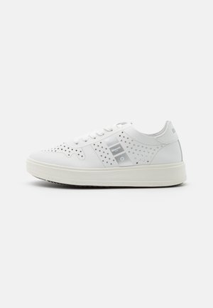 Zapatillas blancas con patrones de estrellas perforados, material sintético suave, acolchado en el collar y suela texturizada. Presenta un parche con el logo en el lateral.
