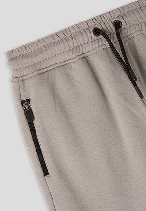 Jasnoszare spodnie dresowe z elastycznym pasem i sznurkiem, bocznymi kieszeniami na zamek oraz gładką teksturą z mieszanki bawełny. Szwy wykończone przeszyciami.