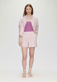 Helles rosa gestreiftes Button-Up-Hemd, lila Tanktop und passende Shorts mit Taschen, kombiniert mit beigen, sandalettenartigen Schuhen. Glatte Texturen.