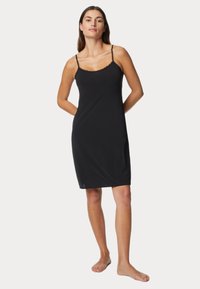 Vestido negro de tirantes finos y con encaje en el escote. Está hecho de una tela suave y cae justo por encima de la rodilla. Diseño simple.