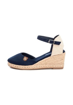 Sandalia cuña azul marino con tacón tejido en beige, tira ajustable en el tobillo con hebilla y pequeño emblema decorativo en el lateral.