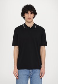 Polo negru cu un guler cu două butoane, mâneci scurte, guler cu dungi albe și o croială lejeră. Materialul pare moale și neted.