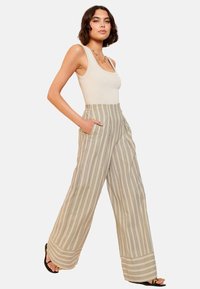 Pantaloni largi cu dungi în bej, având linii verticale subțiri, dotati cu un brâu elastic și buzunare laterale. Textură de stofă netedă.