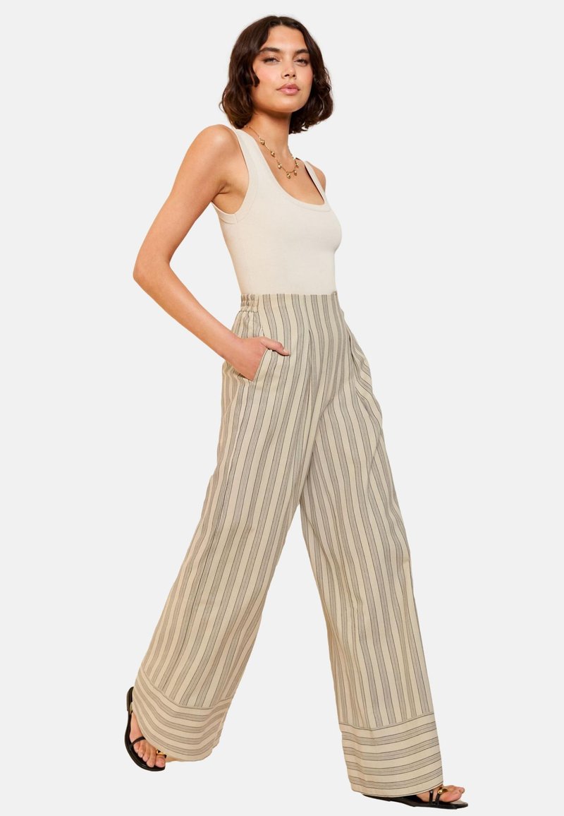 Pantaloni largi cu dungi în bej, având linii verticale subțiri, dotati cu un brâu elastic și buzunare laterale. Textură de stofă netedă.