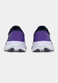 Lilla og svarte treningssko med en polstret hvit såle og teksturert stoffoverdel, med reflekterende detaljer på hælen.