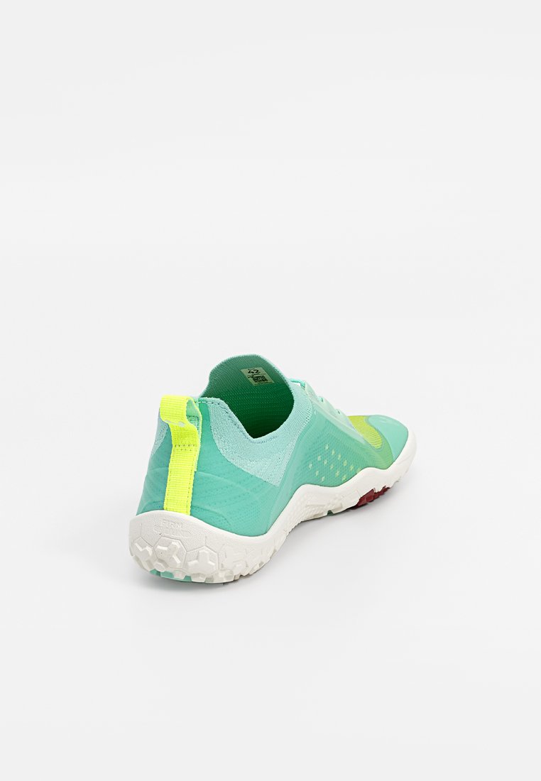 Zapatilla deportiva verde y azul claro con un upper texturizado, acentos amarillos y una suela de goma blanca que presenta patrones hexagonales.