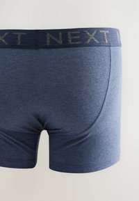 Mäns marinblå boxer-shorts tillverkade av mjukt, stretchigt tyg med en vävd elastisk midjeväv där "NEXT" är tryckt med metalliska bokstäver.
