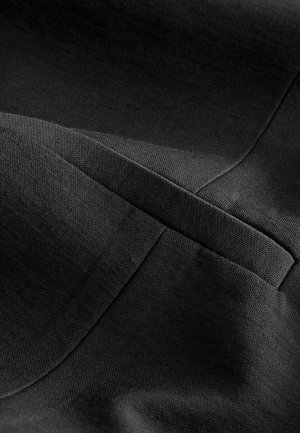 Svart tyg med en texturerad yta, med vikta sektioner och en subtil glans. Materialet verkar tätt och strukturerat.