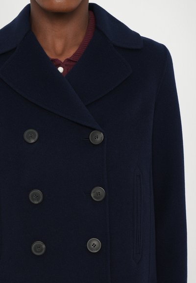 Cappotto peacoat in lana blu navy con design doppiopetto, dotato di grandi bottoni neri e colletto a risvolto. Tessuto testurizzato e tasche inclinate.