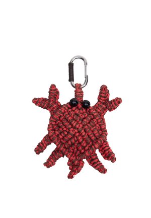 Czerwono-czarny, pleciony breloczek w kształcie kraba z czarnymi oczkami z koralików i metalowym karabińczykiem na białym tle.