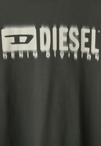 Svart bomull T-skjorte med stort hvitt "DIESEL"-logo og "DENIM DIVISION"-tekst, trykket med gradient fading-effekt. Rund hals.