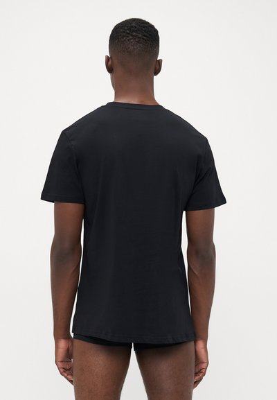 T-shirt noir à col rond fabriqué en tissu lisse, à manches courtes et à coupe classique. Design minimaliste sans logos ni motifs visibles.