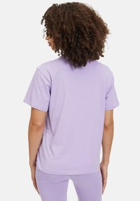 T-shirt di cotone lilla con maniche corte, vestibilità comoda e scollo rotondo. Texture liscia e design semplice.