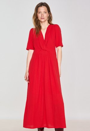 Red, knee-length dress with short sleeves, a V-neckline, and a knot detail at the waist, featuring a flowing, textured fabric.