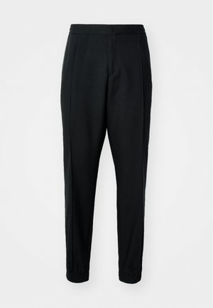 Svarta tapered byxor med slätt tyg, elastisk midja och mudd. Har veck framtill för en skräddarsydd look.