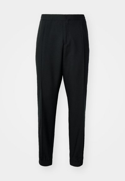 Pantalones negros ajustados con una textura suave, cintura elástica y puños. Presentan pliegues en la parte delantera para un look elegante.