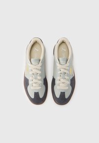 Ténis com um mix de camurça cinza claro e azul-marinho, atacadores creme e sola de borracha. Apresentam o logótipo da Puma e um design texturizado nas laterais.