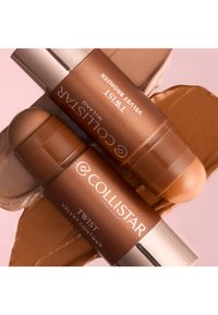 Deux sticks contour et bronzer Collistar Milano Twist Velvet sur des échantillons de crème bronze et beige sur fond rose.