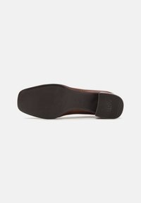Brown leather shoe sole featuring a flat, textured black rubber base with horizontal grooves and embossed branding on the side.