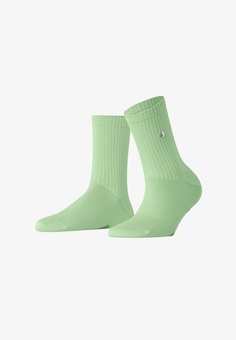 Chaussettes en coton vert avec une texture côtelée, longueur mi-mollet, et un petit logo près de la cheville. Tissu lisse et couleur uniforme.