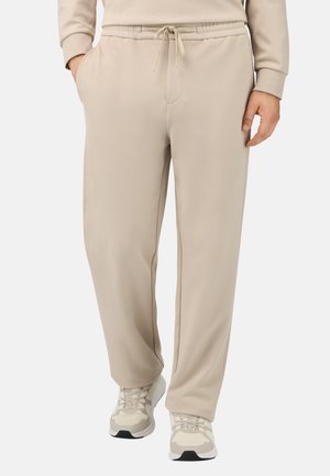 Beige joggingsbroeken van zacht materiaal met een elastische tailleband en verstelbaar trekkoord, voorzien van zijzakken en een relaxte pasvorm.