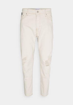 Jasno beżowe dżinsy w slim fit, z przetarciami z przodu, pięcioma kieszeniami i zapięciem na guziki.