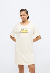 Φόρεμα από βαμβάκι σε κρεμ απόχρωση με κοντά μανίκια και φαρδιά εφαρμογή. Διαθέτει τυπωμένο κείμενο και κίτρινο γραφικό λεμονιού στο μπροστινό μέρος.