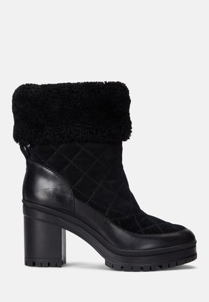 Czarne, pikowane zamszowe botki za kostkę z futrzanym mankietem i grubym obcasem. Posiadają gładką skórzaną boczną wstawkę oraz teksturowaną gumową podeszwę.