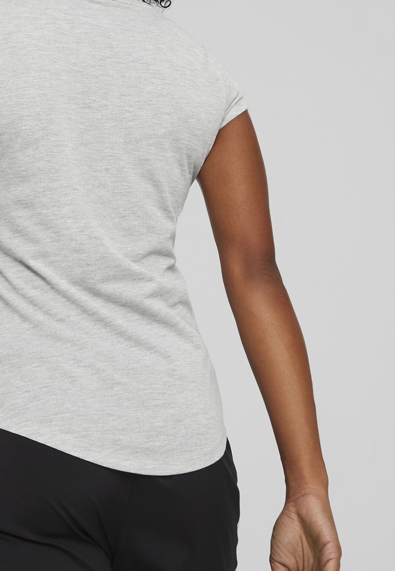 Camiseta gris de manga corta con dobladillo curvado, hecha de un tejido suave y texturizado. El diseño presenta costuras mínimas y un corte relajado.
