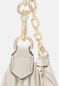 Sac à main en cuir beige clair avec une finition texturée, comprenant des éléments en métal doré et un détail de bandoulière en chaîne, rehaussé par un panneau plat cousu.