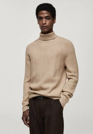 Beige Strickpullover mit Rollkragen und gerippter Textur, getragen mit dunkelbraunen Hosen. Weicher Stoff, taillierter Schnitt und lange Ärmel.