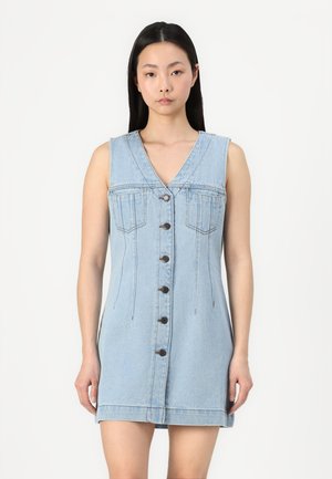 Lichtblauwe denim mouwloze jurk met een V-hals, knoopsluiting aan de voorkant, twee borstzakken en gestikte details langs de zijkanten.
