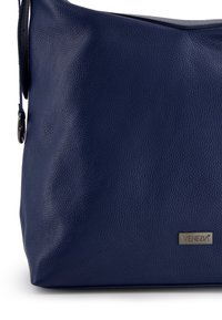 Marineblaue Lederhandtasche mit strukturierter Oberfläche, ausgestattet mit einem dunklen Riemen und einer metallischen Logoplatte. Glatte, strukturierte Form.