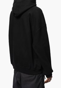 Sweat à capuche noir oversize avec capuche à cordon de serrage, poignets et ourlet côtelés. Tissu doux et texturé avec un design simple et sans couture.