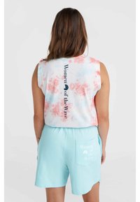 Weißes Baumwoll-Tanktop mit rot-blauem Batikdesign, bedruckt mit dem Text "Women of the Wave". Kombiniert mit hellblauen Shorts mit Taschenprint.