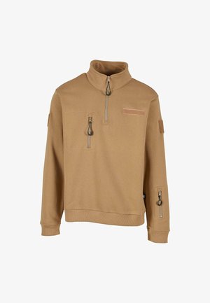 Tan fleece pullover med høj krave, front kvart lynlås og to lynlåslommer. Har et mærke på fronten og en lomme på ærmet.