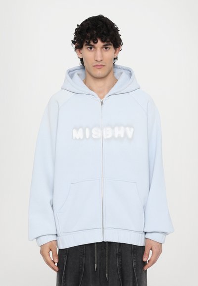 Světle modrá zapínací mikina s fleecovou strukturou, velkými předními kapsami a bílým 3D logem "MISBHV" na hrudi.