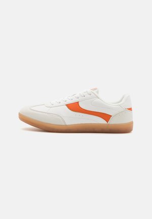 Hvid lave sneakers med orange side stribe og gummisål, vist i sideprofil på en ensfarvet baggrund.