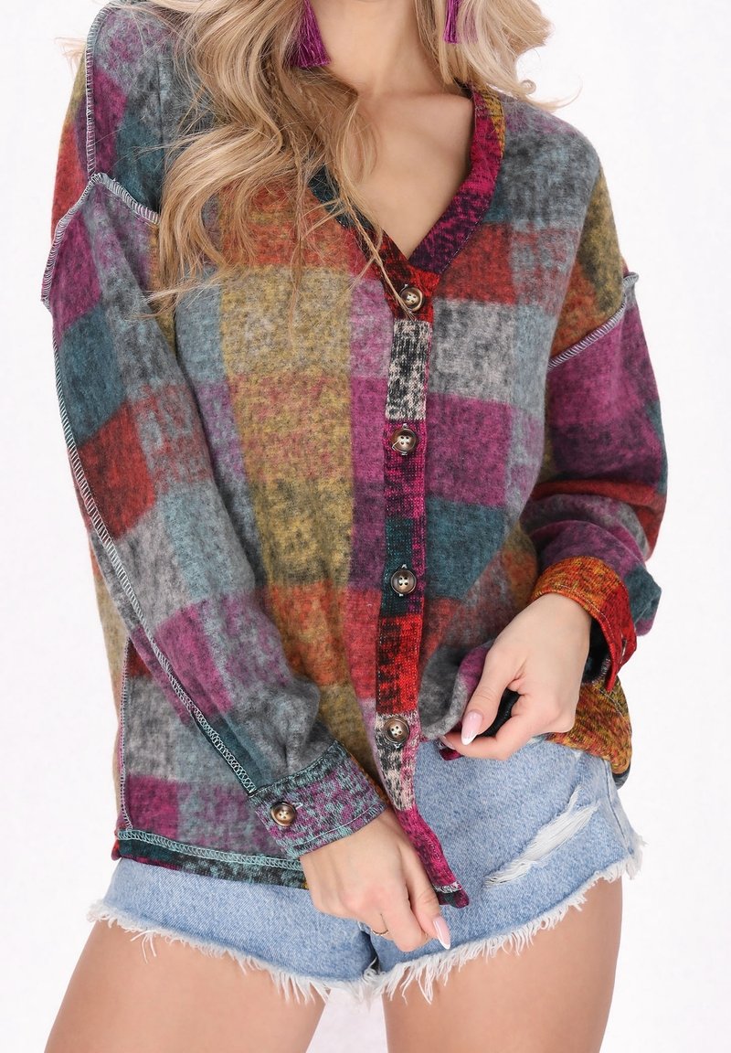 Femme portant une chemise à carreaux multicolores à manches longues et un short en jean bleu clair effiloché.