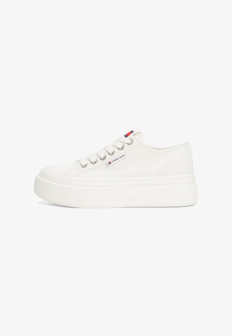 White canvas sneakers with a thick, textured platform sole. Features include lace-up design, silver eyelets, and a small logo tag.