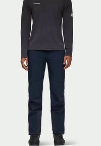 Granatowe spodnie trekkingowe o gładkiej fakturze, wyposażone w wyprofilowane kolana i wzmocnione szwy. Połączone z czarną bluzą z długim rękawem.