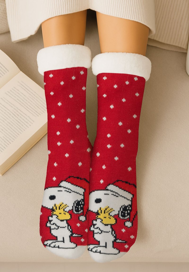 Calze rosse a maglia con pois bianchi, decorate con un design di cartone animato raffigurante un cane con un cappello di Babbo Natale che tiene un uccellino giallo, polsini bianchi in pile.