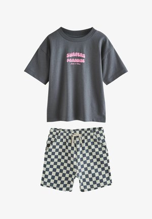 Sötétszürke rövid ujjú póló rózsaszín "SURFERS PARADISE Catch A Wave" felirattal és fekete-fehér kockás, zsinórral állítható rövidnadrággal.