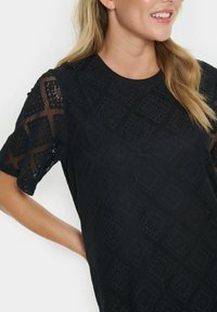 Black short-sleeve top featuring a textured lace design with diamond patterns and a round neckline. The fabric is lightweight and breathable.