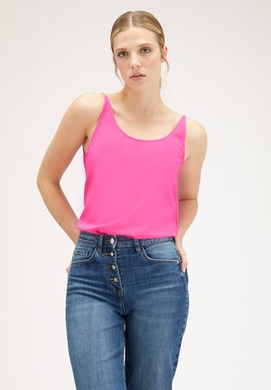 Top sin mangas fucsia con tirantes finos, textura suave, combinado con unos vaqueros de mezclilla azul de cintura alta con cierre de botones y bolsillos delanteros.