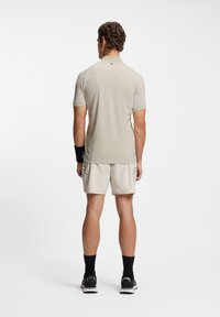 Light beige athletic shirt and shorts, fitted design with short sleeves, two accent stripes on shorts. Worn with black socks and shoes.