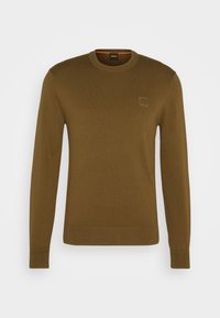 Pull marron tricoté avec un col rond, des manches longues et des poignets côtelés. Comprend un petit écusson logo sur la poitrine.