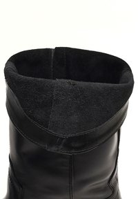 Stivaletto in pelle nera con soffietto in suede. Texture liscia con dettagli di cuciture e apertura arrotondata nella parte superiore.